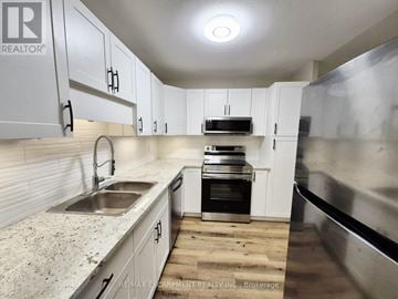 Brantford condo for rent - A kitchen with white cabinets and a granite counter top.