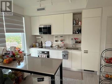 Barrie (City Centre) condo for rent - A kitchen with white cabinets and a black countertop.