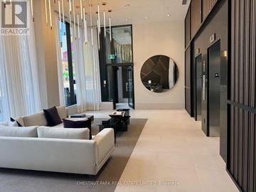 Toronto (Wychwood) condo for rent - A modern living room with a white sofa and a large mirror on the wall.