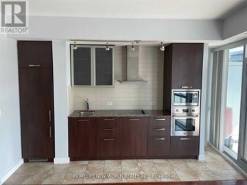 Toronto (Waterfront Communities) condo for rent - A kitchen with brown cabinets and a stainless steel oven.