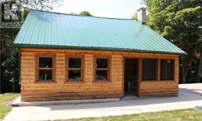 Prince Edward County (North Marysburg Ward) apartment for rent - A small wooden cabin with a green roof is surrounded by trees.