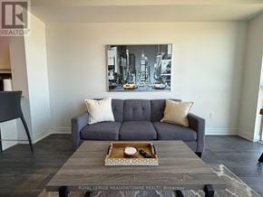 Milton (De Dempsey) condo for rent - A grey couch with two pillows sits in a room with a cityscape picture on the wall.