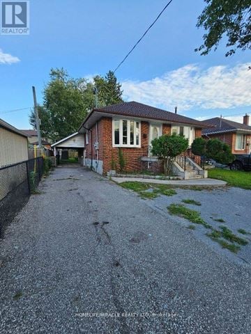 Toronto (Wexford-Maryvale) apartment for rent - A gravel driveway leads to a brick house with a fence on one side.