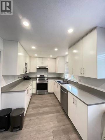 Coquitlam apartment for rent - A modern kitchen with white cabinets and a grey floor.