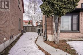 Pickering (Amberlea) apartment for rent - A snow-covered sidewalk leads to a brick building with a tree in front.
