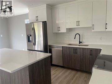 Azilda apartment for rent - A modern kitchen with a stainless steel refrigerator and wooden cabinets.