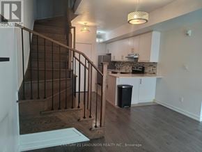 Toronto (Weston) townhouse for rent - A staircase with a metal railing leads to a kitchen area.