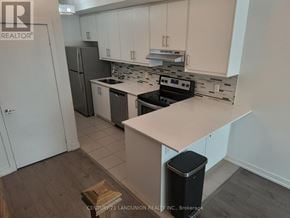 Toronto (Weston) townhouse for rent - A kitchen with white cabinets and a black trash can.