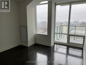 Toronto (Annex) condo for rent - A room with a large window overlooking a cityscape.