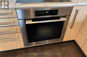 Toronto (Annex) condo for rent - A modern stainless steel oven with a digital display is set in a kitchen with wooden cabinets.
