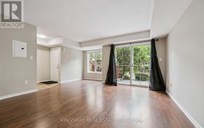 Oakville (Ro River Oaks) townhouse for rent - A spacious room with wooden flooring and a sliding glass door leading to a garden.