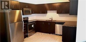 Oakville (Ro River Oaks) townhouse for rent - A kitchen with a stainless steel refrigerator, microwave, oven, and sink.