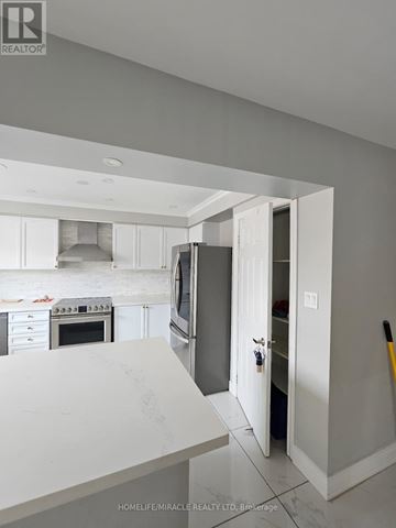 Brampton (Sandringham-Wellington) apartment for rent - A kitchen with white cabinets and a white countertop with a refrigerator and oven in it.