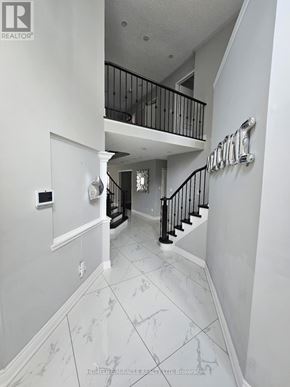 Brampton (Sandringham-Wellington) apartment for rent - A hallway with a marble floor and a staircase with a black railing.