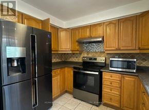 Barrie (Grove East) apartment for rent - A kitchen with wooden cabinets and a black refrigerator.