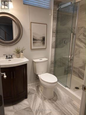 Hamilton (Stoney Creek) apartment for rent - A white toilet in a bathroom with a glass shower door.