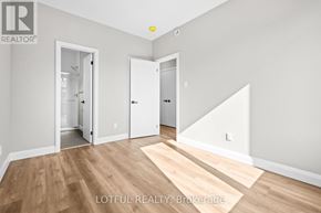 Ottawa apartment for rent - A room with wooden flooring and white walls, with a door on the right and a hallway leading to another room.