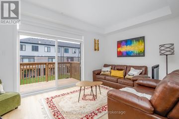 Brantford townhouse for rent - A living room with a brown leather couch and a red and white rug.
