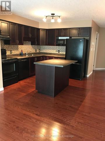 Waterloo townhouse for rent - A kitchen with dark wood cabinets and a black refrigerator.