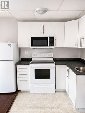 Collingwood townhouse for rent - A white kitchen with a black countertop and a white fridge.