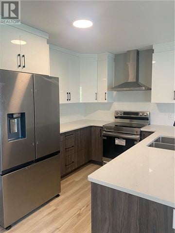 Azilda apartment for rent - A modern kitchen with a stainless steel refrigerator and wooden cabinets.