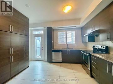 Markham (Commerce Valley) townhouse for rent - A kitchen with dark wood cabinets and a white dishwasher.