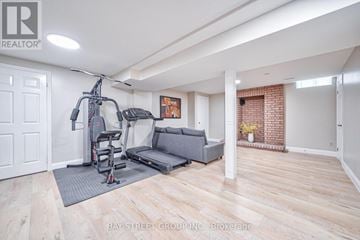 Vaughan (Maple) apartment for rent - A spacious living room with a grey sofa and a gym setup.