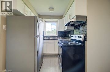 London apartment for rent - A kitchen with a black fridge and stove top oven.