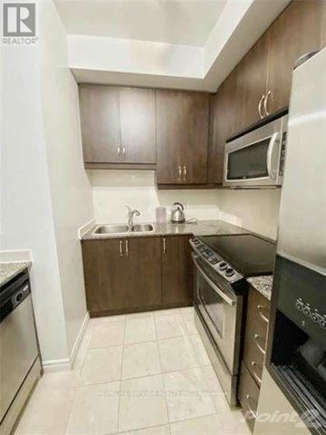 Toronto (Willowdale East) condo for rent - A kitchen with brown cabinets and white appliances.