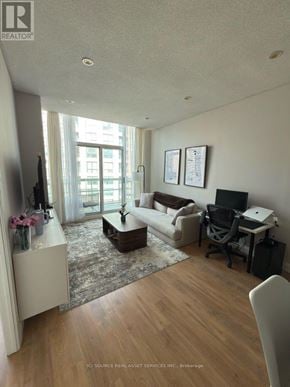Toronto (Willowdale West) condo for rent - A living room with a couch, a coffee table, a television, and a desk with a chair.