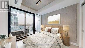 Toronto (Moss Park) condo for rent - A bedroom with a large bed and a view of the city.