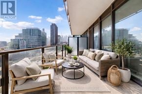 Toronto (Moss Park) condo for rent - A modern balcony with a sofa, chairs, and a table with a view of the city.