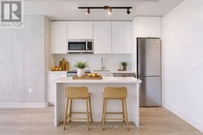 Toronto (Moss Park) condo for rent - A kitchen with white cabinets and a white island with two stools.
