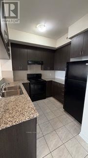 Brampton (Bram West) condo for rent - A kitchen with black appliances and brown cabinets.
