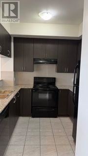 Brampton (Bram West) condo for rent - A black oven in a kitchen with brown cabinets.