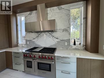 Vancouver apartment for rent - A modern kitchen with a stainless steel stove and marble countertops.