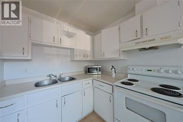 Sarnia townhouse for rent - A white kitchen with a stove and microwave.