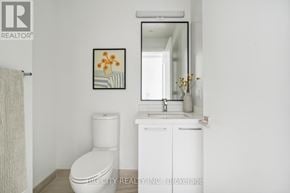 Toronto (Thorncliffe Park) condo for rent - A white bathroom with a toilet, sink, and a framed picture on the wall.