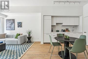 Toronto (Thorncliffe Park) condo for rent - A modern living room with a grey sofa, a black coffee table, and a dining table with green chairs.