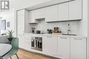 Toronto (Thorncliffe Park) condo for rent - A modern kitchen with white cabinets and a green chair.