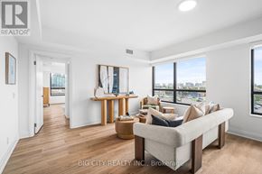 Toronto (Thorncliffe Park) condo for rent - A living room with a couch, a table, and a window overlooking the city.
