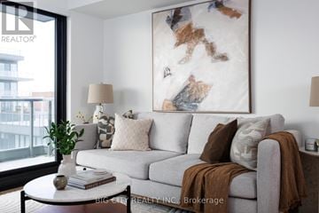 Toronto (Thorncliffe Park) condo for rent - A living room with a grey couch, a white coffee table, and a large abstract painting on the wall.