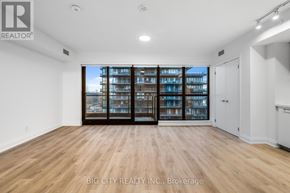 Toronto (Thorncliffe Park) condo for rent - A spacious room with wooden flooring and a large window with a view of a building.