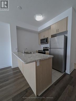 Hamilton (Waterdown) condo for rent - A kitchen with a refrigerator, microwave, and oven.