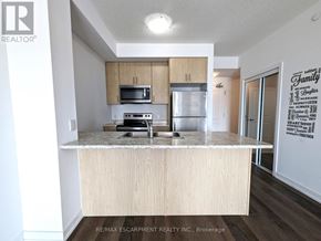 Hamilton (Waterdown) condo for rent - A kitchen with a white counter top and wooden cabinets.