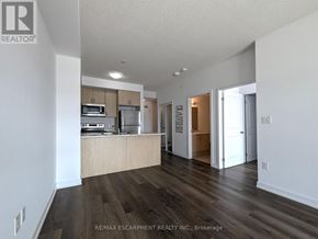 Hamilton (Waterdown) condo for rent - A spacious living room with a kitchen area in the background.