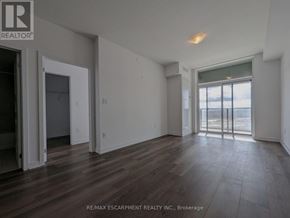 Hamilton (Waterdown) condo for rent - A room with wooden floors and a large window overlooking the water.