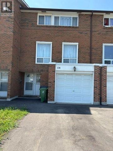 Toronto (Mount Olive-Silverstone-Jamestown) townhouse for rent - A brick building with a white garage door and a green trash can in front.