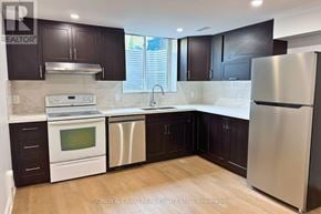 Clarington (Courtice) apartment for rent - A kitchen with white appliances and dark wood cabinets.
