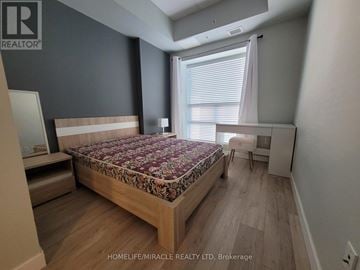 Waterloo condo for rent - A bedroom with a floral bedspread and wooden bed frame.